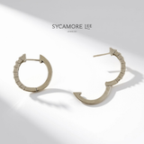 A pair of textured silver hoop earrings by Sycamore Lee Jewelry, displayed on a clean white background with artistic diagonal shadows.
