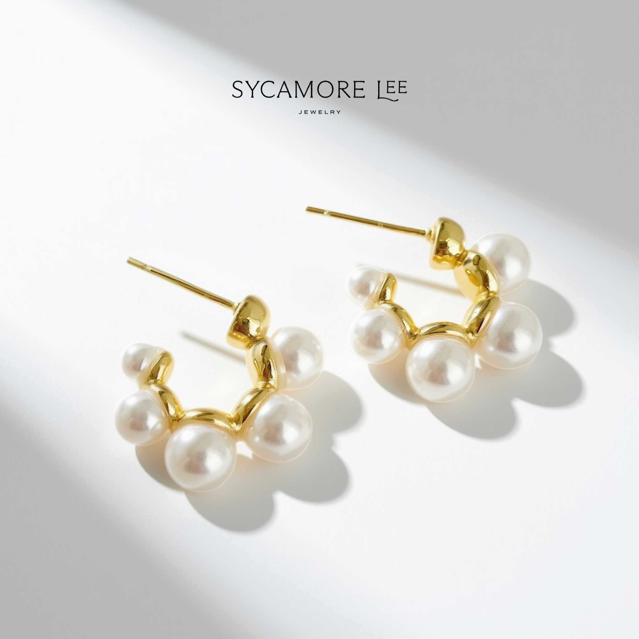 A pair of gold and pearl cluster earrings by Sycamore Lee Jewelry, displayed on a clean white background with soft diagonal shadows.