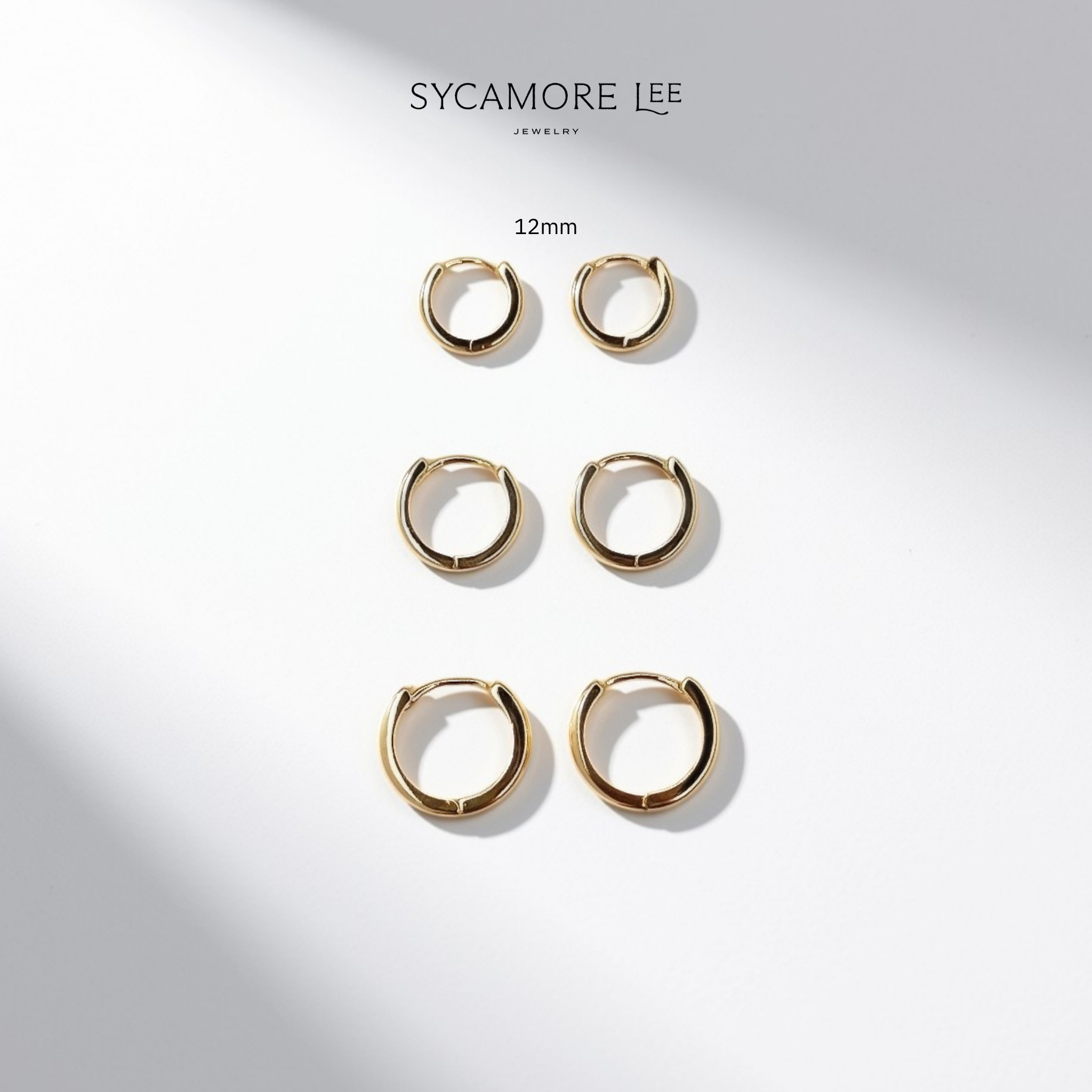 Six pairs of gold-plated 12mm hoop earrings arranged in a vertical column on a white background with soft diagonal shadows. The brand name 'SYCAMORE LEE' and the text '12mm' are printed above the earrings.