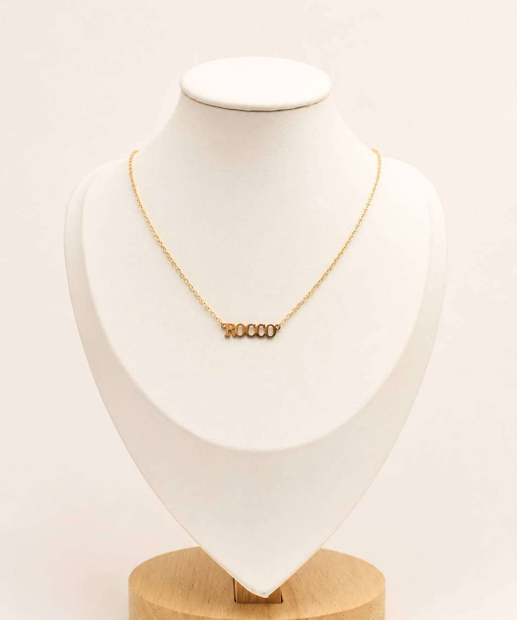 Gold necklace on a white bust with a wooden base against a beige background