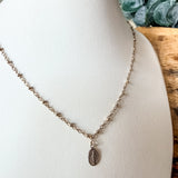 A delicate mixed metal chain necklace with a small oval religious pendant, displayed on a white jewelry bust.