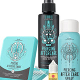 BASE Laboratories piercing aftercare kit including a black hypochlorous acid spray bottle, a light blue aftercare spray canister, a turquoise aftercare swabs tin, a small yellow piercing bump solution dropper bottle, and clear plastic swab tips on a white background.