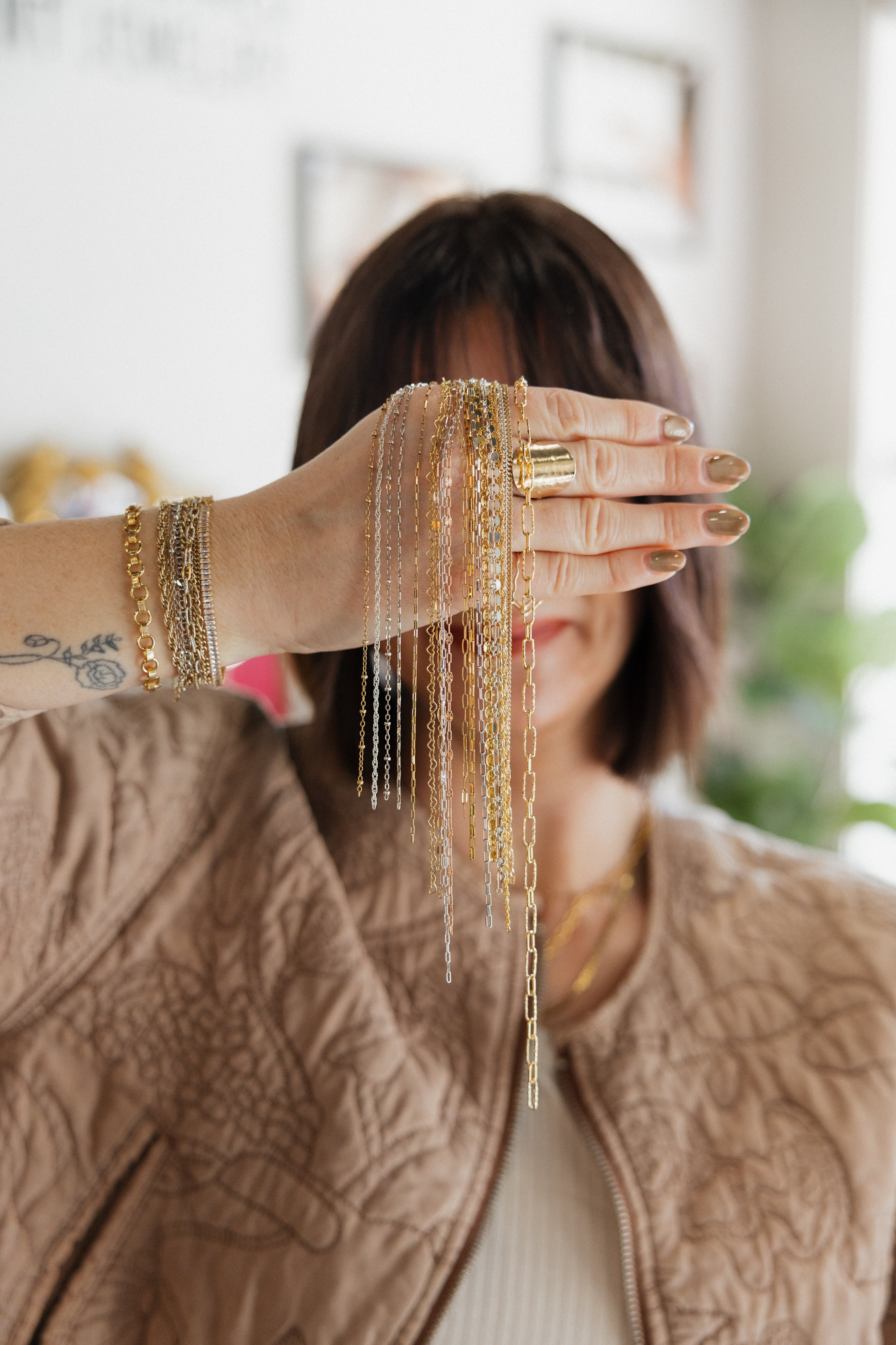 Person wearing multiple gold bracelets and rings with a blurred background